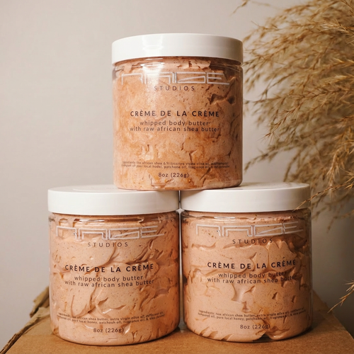 Three jars of 'Rage & Radiance' whipped body butter stacked on a wooden surface with a neutral background.